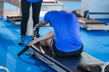 Çocuk spor salonundaki spor öncesi esneme hareketleri yaparak bacaklarını uzatarak oturuyor..