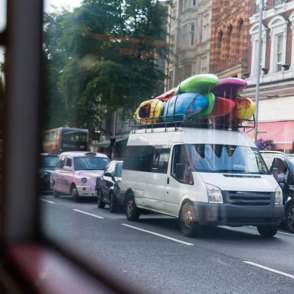 Çatıda Bir Sürü Renkli Kanosu Olan Beyaz Minibüs Trafikte — Stok fotoğraf