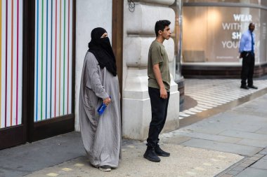 Londra, Birleşik Krallık- Haziran 2019: Sokak Fotoğrafçılığı: Orta yaşlı Müslüman Kadın ve Londra 'nın merkezinde bir çocuk.