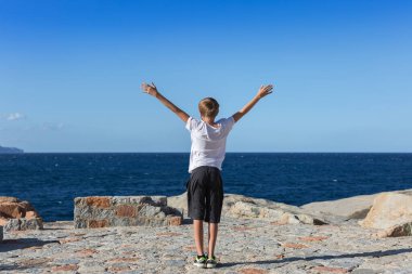 Dalgalı Mavi Deniz 'in Önündeki 12 yaşındaki çocuk kollarını gökyüzüne kaldırdı..