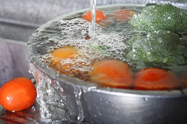 Lavado de verduras frescas en el fregadero Imagen de archivo