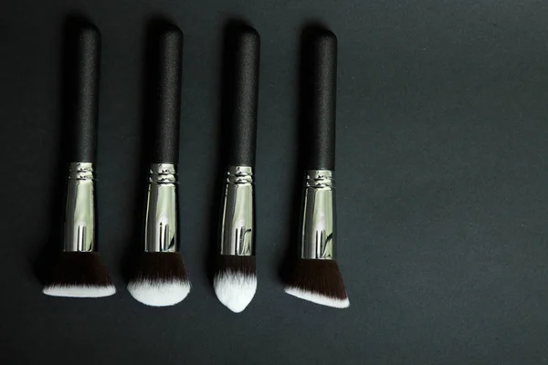 Professional makeup brushes on a black background, natural cloth
