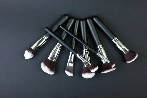 Professional makeup brushes on a black background, natural cloth