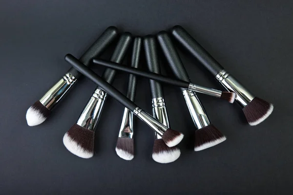 Cepillos de maquillaje profesionales sobre fondo negro, tela natural — Foto de Stock