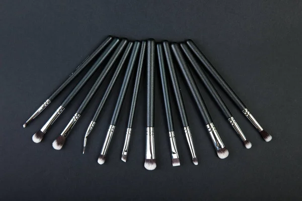 Professional makeup brushes on a black background, natural cloth