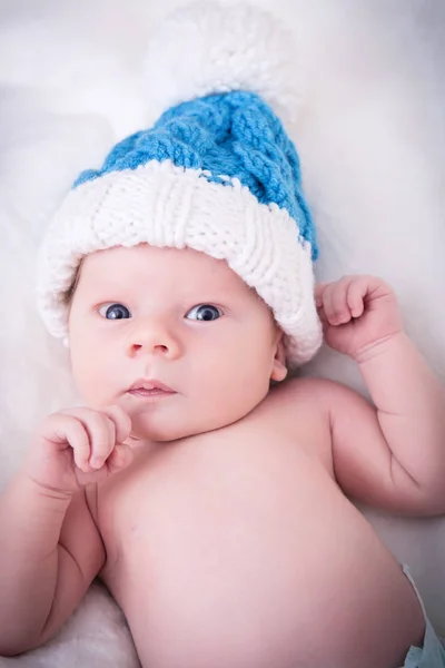 Een schattige kleine baby is op zoek naar de camera en draagt een witte hoed. de baby zou een jongen of meisje en heeft blauwe ogen. gebruiken voor een concept ouderschap of liefde. — Stockfoto