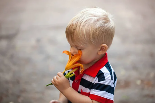 Jongetje ruiken een frisse lente bloem lelie — Stockfoto