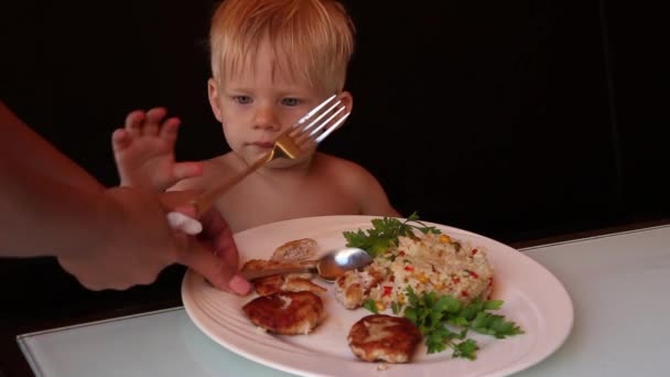 Een kleine jongen eet voedsel in een café, close-up — Stockvideo