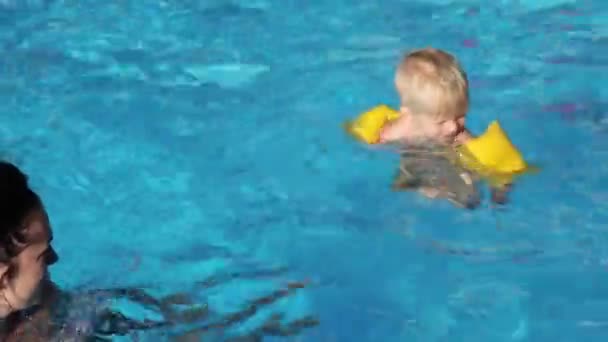 Uma criança toma banho com sua mãe na piscina, família — Vídeo de Stock