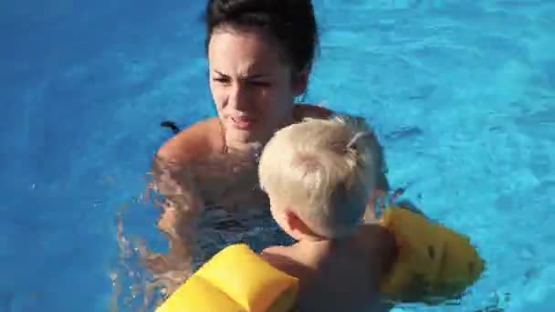 Uma criança toma banho com sua mãe na piscina, família — Vídeo de Stock