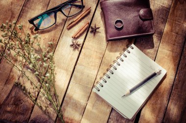 Not defterleri, kalemleri, ekipman hafifçe parlayan sabah güneşi ile ahşap zemin üzerinde.