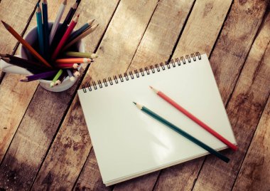 Not defterleri, kalemleri, ekipman hafifçe parlayan sabah güneşi ile ahşap zemin üzerinde.