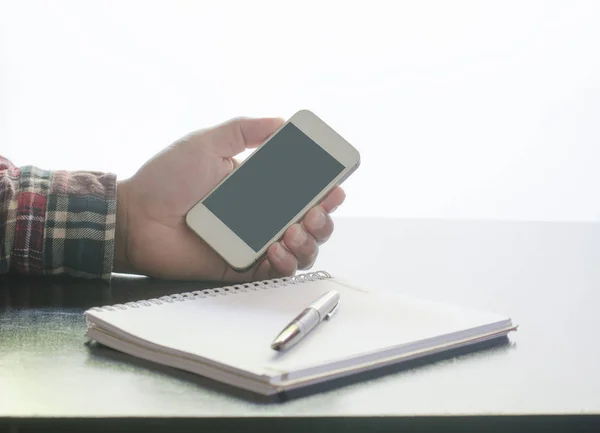 Geschäftsmann hält Smartphone und Notizbuch auf Holz — Stockfoto