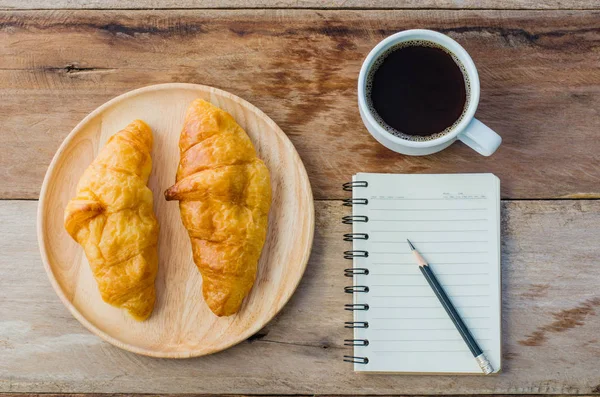 Croissants caderno de café e lápis na mesa de madeira - tom vintage — Fotografia de Stock