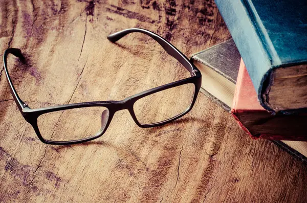 Gafas colocadas sobre una mesa de madera con libros . —  Fotos de Stock