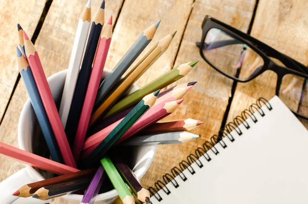 Notebooks, pencils, Equipment on the wooden floor with the morning sun shining faintly. — Stock Photo, Image