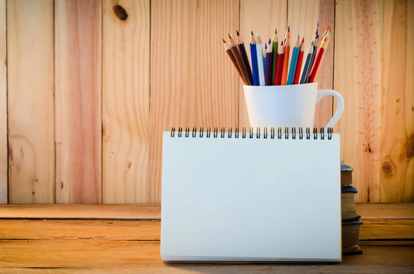 Lápis de cor e caderno de esboços na mesa de madeira — Fotografia de Stock