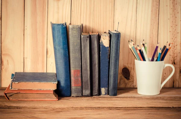 Lápis de cor e livro velho sobre mesa de madeira — Fotografia de Stock