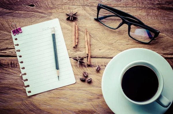 Blocchi note, matite, bicchieri, tazze da caffè su un tavolo di legno . — Foto Stock