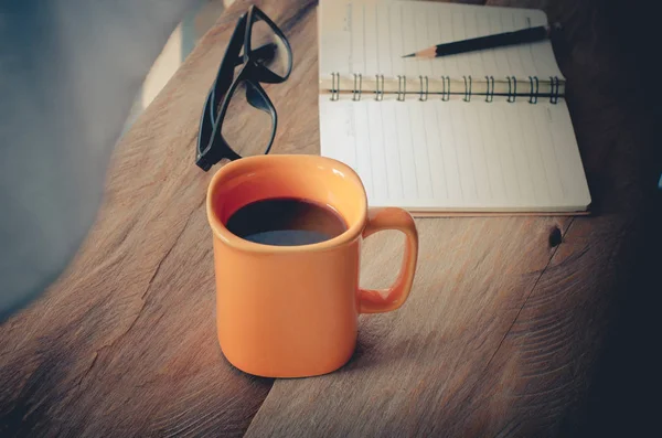 Taccuini, matite, tazze da caffè su un tavolo di legno vicino alla finestra . — Foto Stock