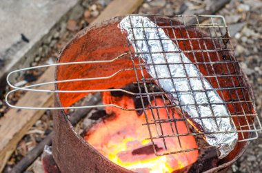 Ocakta folyo sarılı ızgara balık.