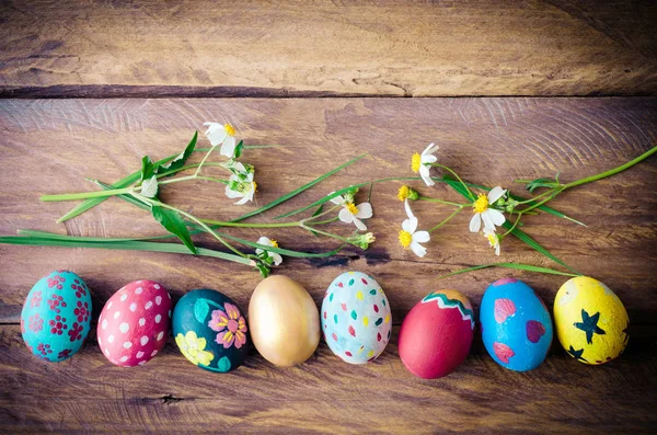 Easter eggs and flowers placed on a wooden floor.