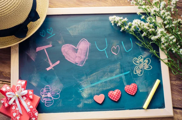 Quadro negro com palavras escritas em choque que o "Eu te amo" e um coração floral foi colocado ao lado da placa - o conceito de Dia dos Namorados . — Fotografia de Stock
