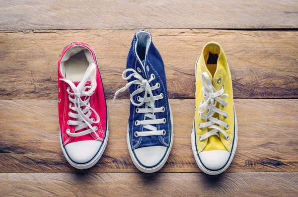 Multicolored sneakers on wooden floor — Stock Photo, Image
