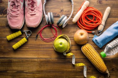 Ahşap arka plan üzerinde egzersiz donanımları ve sağlıklı gıda ile fitness kavramı.