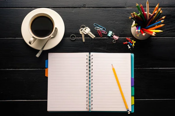 Lápis de caderno e xícara de café em mesa de madeira — Fotografia de Stock