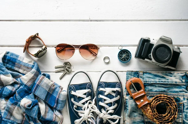 Ropa para viajar, colocada en un suelo de madera blanco . — Foto de Stock