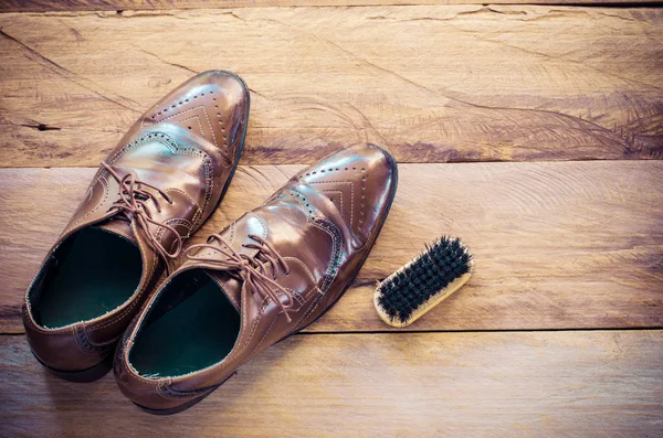 Sapatos de couro, escovas, colocados num chão de madeira . — Fotografia de Stock