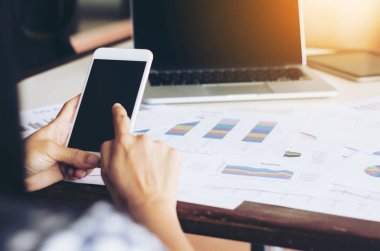 Smartphone ve dizüstü bilgisayar kullanarak çalışan genç kadın.