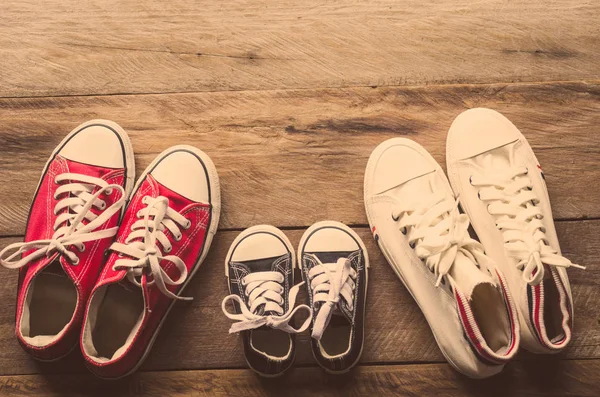 Tres pares de zapatos yacen en el piso de madera de la familia, padres e hijos para hacer juntos . — Foto de Stock