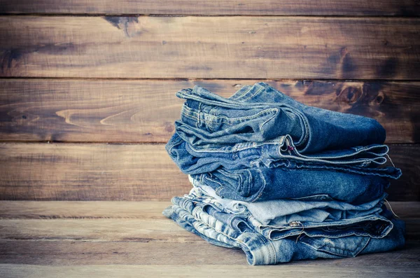 Pila de jeans sobre un fondo de madera — Foto de Stock