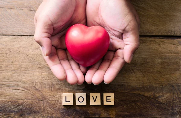 Mani uomini dando cuore rosso e parola per amore — Foto Stock