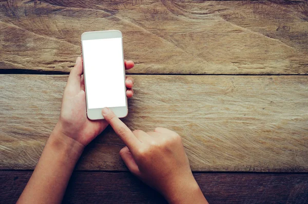 Ręka trzyma inteligentny telefon na białym tle na podłoże drewniane — Zdjęcie stockowe