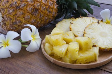 Güzel çiçek ile dekore edilmiş ahşap plaka üzerinde ananas dilimlenmiş