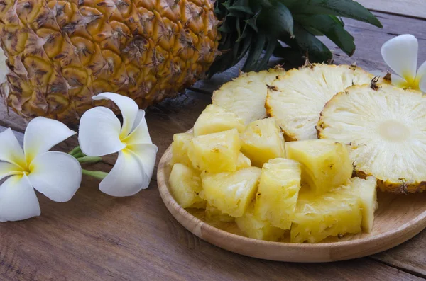 Güzel çiçek ile dekore edilmiş ahşap plaka üzerinde ananas dilimlenmiş