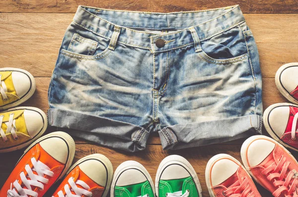 Short jeans for teenage girls and sneakers on wooden floors. — Stock Photo, Image