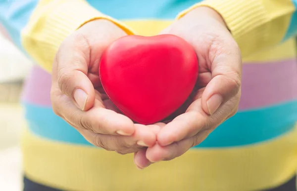 Mani donne dando cuore rosso — Foto Stock