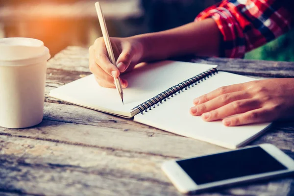 Ręka jest pisanie notebook ołówek i filiżankę kawy — Zdjęcie stockowe