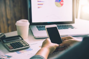 akıllı telefon ve açık alan ofis dizüstü bilgisayar üzerinde çalışan bir iş adamı. Toplantı rapor devam ediyor.