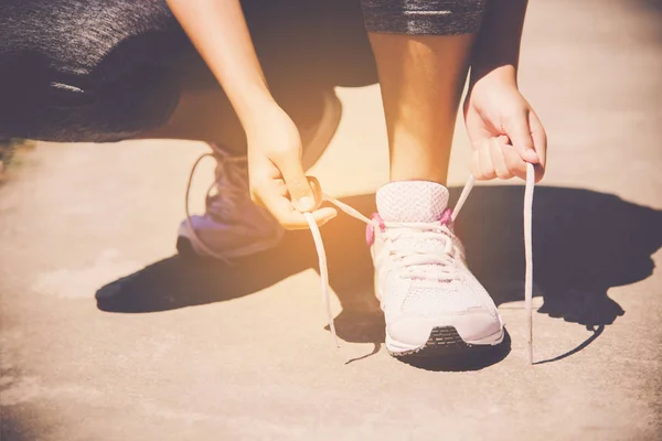 Hands of a young woman shoelace and sneakers. Shoes standing on — Stock Photo, Image