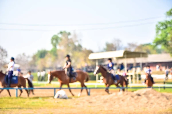 Immagini sfocate di persone che cavalcano cavalli sul campo pratica — Foto Stock