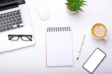 Çalışma masası, laptop, cep telefonu, kalem kahve fincanı ve gözlüklü üst görünüm ofiste.. 