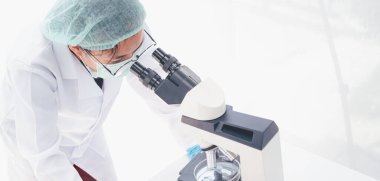 Tıbbi bir laboratuarda mikroskoba bakan kadın bir tıp araştırmacısı. Tıbbi deneysel konsept