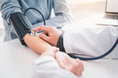 Doktor hastanın tansiyonunu ölçüyor.