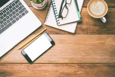 Üst düzey ofis ekipmanları, dizüstü bilgisayar, cep telefonu, fare, defter, ahşap zemindeki kahve fincanı dahil.