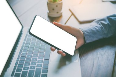 Ev işi için masa başında boş beyaz bir cep telefonuyla el ele tutuşmanın yakın plan görüntüsü..